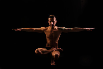 Fototapeta na wymiar Young strong man practices yoga and gymnastics, Eagle posture, balance