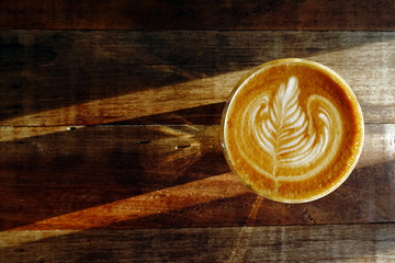 cup of latte art coffee on wooden background