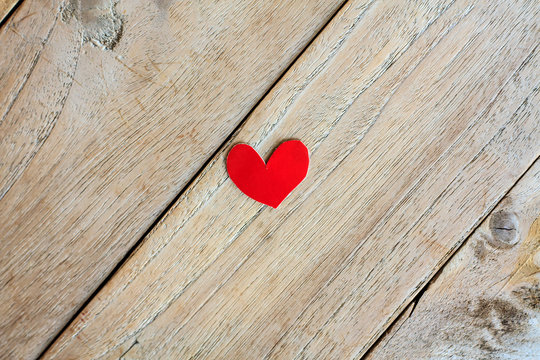 Red paper with heart shape on grunge wooden background