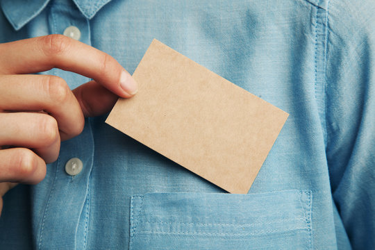 Young man who takes out craft blank business card from the pocket of his shirt