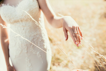 beautiful wedding ring on bride hand touching ear on field in su - 101694556