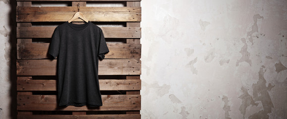 Photo black tshirt  hanging in front of wood background. Wide