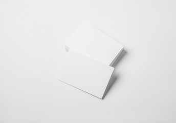 Stack of blank business cards on white background with soft shadows. 