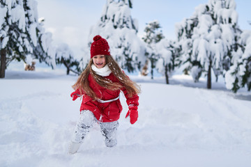 Fototapeta na wymiar Girl runs and rejoices in snowy park