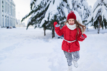 Fototapeta na wymiar Girl jumping for joy in snowy winter park