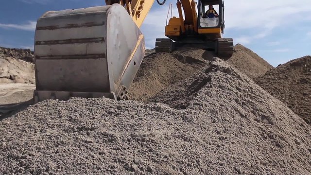 Caterpillar in action.
Excavator is working on construction site in center of the sand pile.
