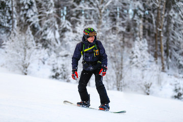 Fototapeta na wymiar Snowboarder in black suit slides down 