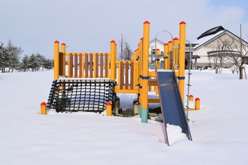 雪国の公園の遊具／雪国の降雪後の公園で、ブランコや滑り台などの遊具を撮影した、冬イメージの写真です。約40cmの降雪後の風景ですが、冬期間は雪が解ける春まで、写真の様に遊休状態となります。