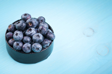 Blueberrys in a bowl on a turquoise wooden table