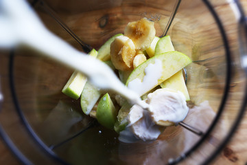 Pouring milk over bananas and apples in a blender. Making healthy shake.
