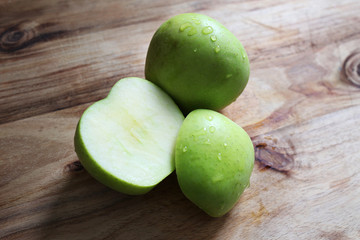 Couple of fresh apples on a wooden board, one of the apples has been cut to show the freshness of the fruit.
