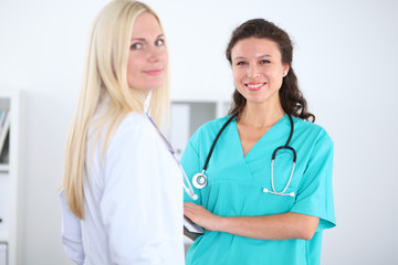 Two confident friendly female doctors sitting at the table and listen to the patient's history . Medical and health care concept