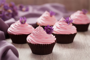 Cupcakes traditional sweet wedding pastry with pink cream and violet flowers in row on vintage...