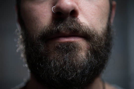 Junger Mann mit Vollbart und Piercing