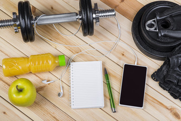 Sport Equipment. Dumbbells, Free Weights, Barbell, Hand Grip, Sport Gloves, Orange Juice, Smart Phone With Earphones And Notebook To Workout Plan On Wooden Table. Sport Fitness Background