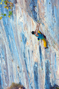 Side View of Male Climber hanging on vertical Rock