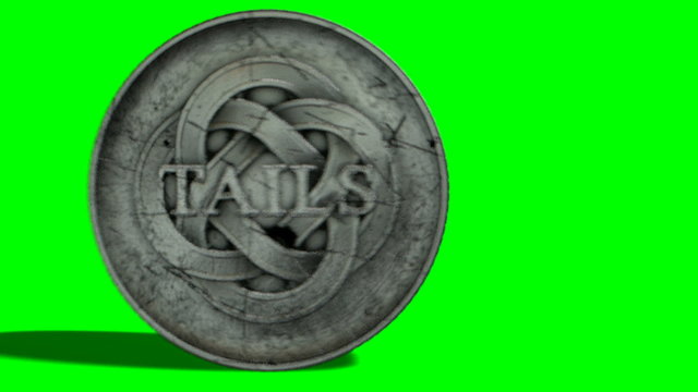 A worn antique silver coin with a heads and tails side spinning on a green screen background
