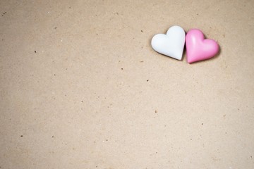 Obraz premium Two small wooden heart (white,pink) on paper background