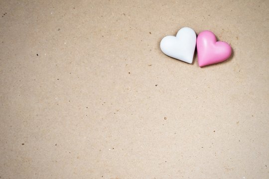 Two small wooden heart (white,pink) on paper background