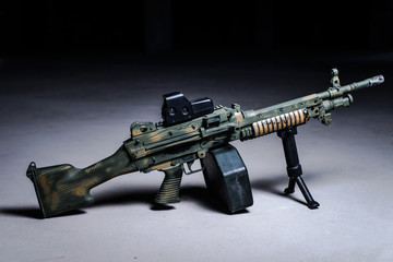 Machine gun on the ground/Machine gun with camouflage pattern on the ground on dark background