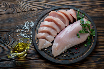 Whole and sliced chicken breast filet in a rustic wooden setting