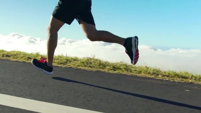Young Man Running on Mountain Road Above the Clouds. Slow Motion HD. Healthy Outdoor Lifestyle.