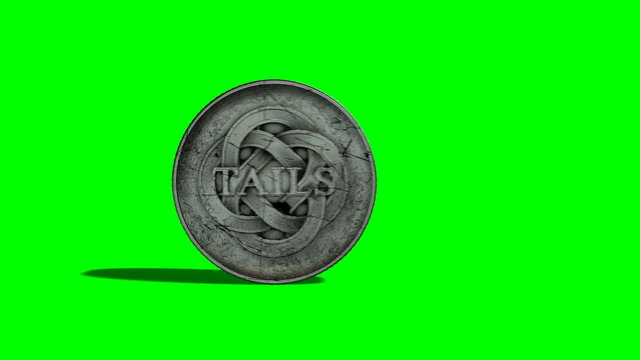 A worn antique silver coin with a heads and tails side spinning on a green screen background
