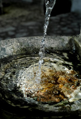 Trickle of water flowing in old granite fountain