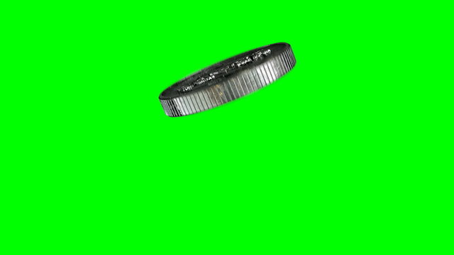 A worn antique silver coin with a heads and tails side flipping into the air on a green screen background