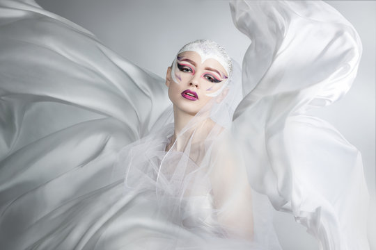 woman with bright creative make-up in a white cloth flying. A girl holding a flying white cloth