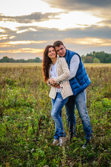 Naklejka na ściany i meble Young couple holding hands in a meadow at sunset