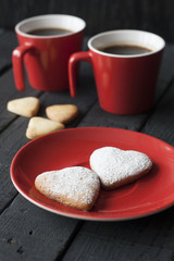 Red cup and cookie hearts on a black background
