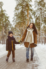 Fototapeta na wymiar Happy family in winter clothing. Smiling mother and son walk at the park