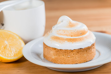 lemon cake on a saucer with a cappuccino on a wooden background