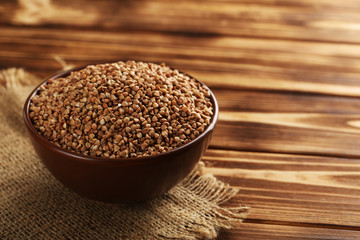 Buckwheat seeds in bowl on a brown wooden table