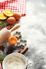 Christmas tree branch with dried oranges, cinnamon, eggs, flour and anise star on wooden table