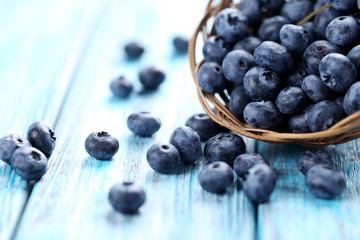Tasty blueberries in basket on a blue wooden table