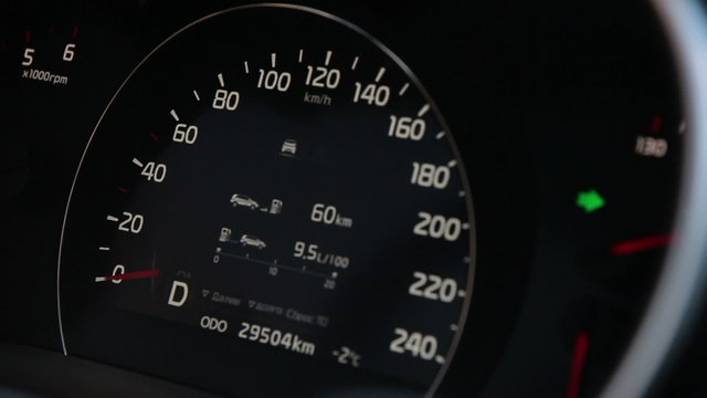 Car speedometer with blinking turn signal on dashboard, close up
