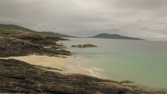 Stunning aerial shot on the Isle of Harris, Scotland near the coast flying over a small fishing boat
