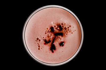 red cocktail with foam  and roses petal seen from above