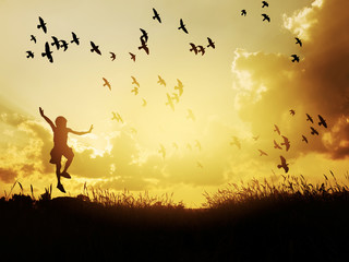 Happy child jumping with birds in sunset sky.