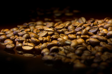 
whole coffee beans on a black mirrored background with reflection of fireю
