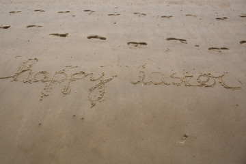 Happy Easter handwritten in sand on a beach