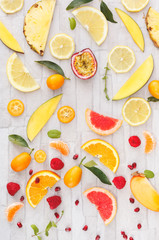Collection of fresh whole and sliced yellow, orange and red fruits on white rustic background