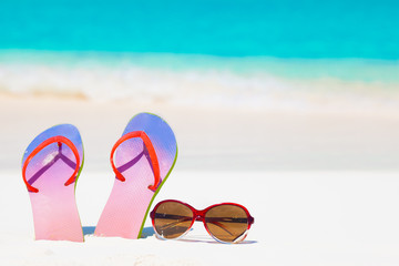 bright flip flops and sunglasses on a tropical sea resort background