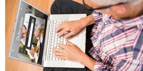 Composite image of man using laptop while sitting on floor