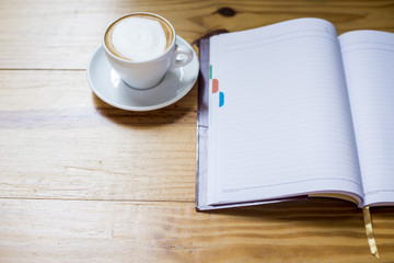 notebook with cup of coffee on wooden desk