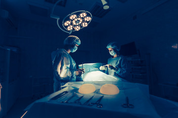 Surgeons team working with Monitoring of patient in surgical operating room. breast augmentation