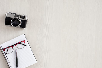 Top view of wooden table with office supplies. Office desk table with notebook,pen,glasses old photo camera 