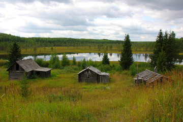 Broken house and bathhouse near a lake in abandoned village